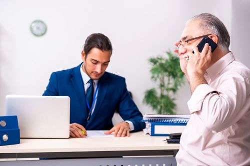 Pensionist telefoniert, Sachbearbeiter am Schreibtisch
